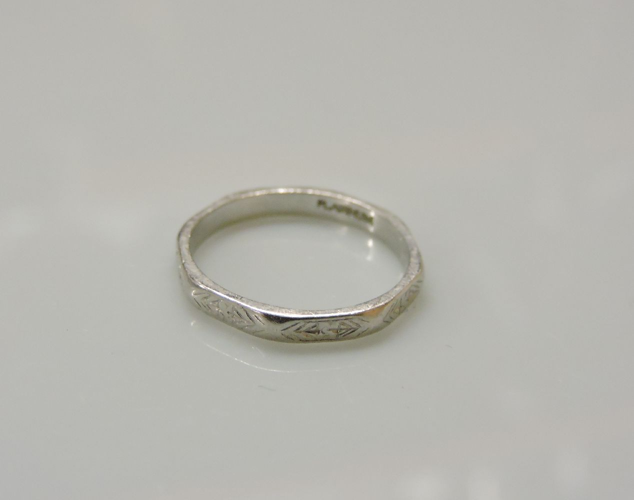 An Art Deco faceted and engraved wedding ring, stamped platinum, 2.67g