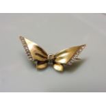 A gold bow brooch, set with rose cut diamond wings