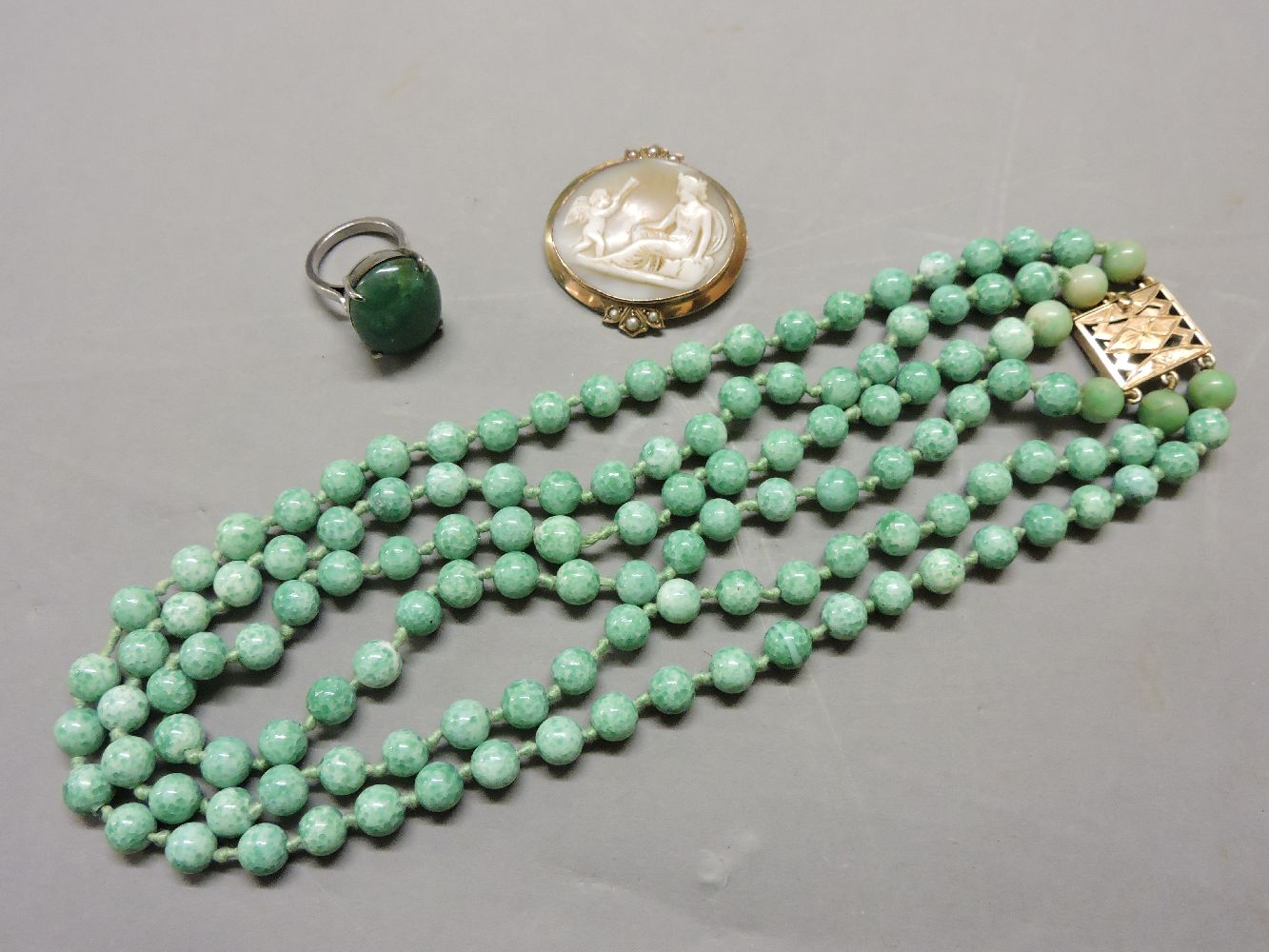 A three row Peking glass bead necklace, with gold clasp set with six jade beads to either side of