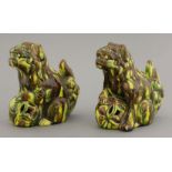 A pair of earthenware sancai Buddhist lions, circa 1880, each crouching over a pierced ball, its