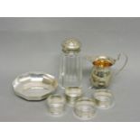A small silver cream jug, a silver caster, silver dish, and four napkin rings