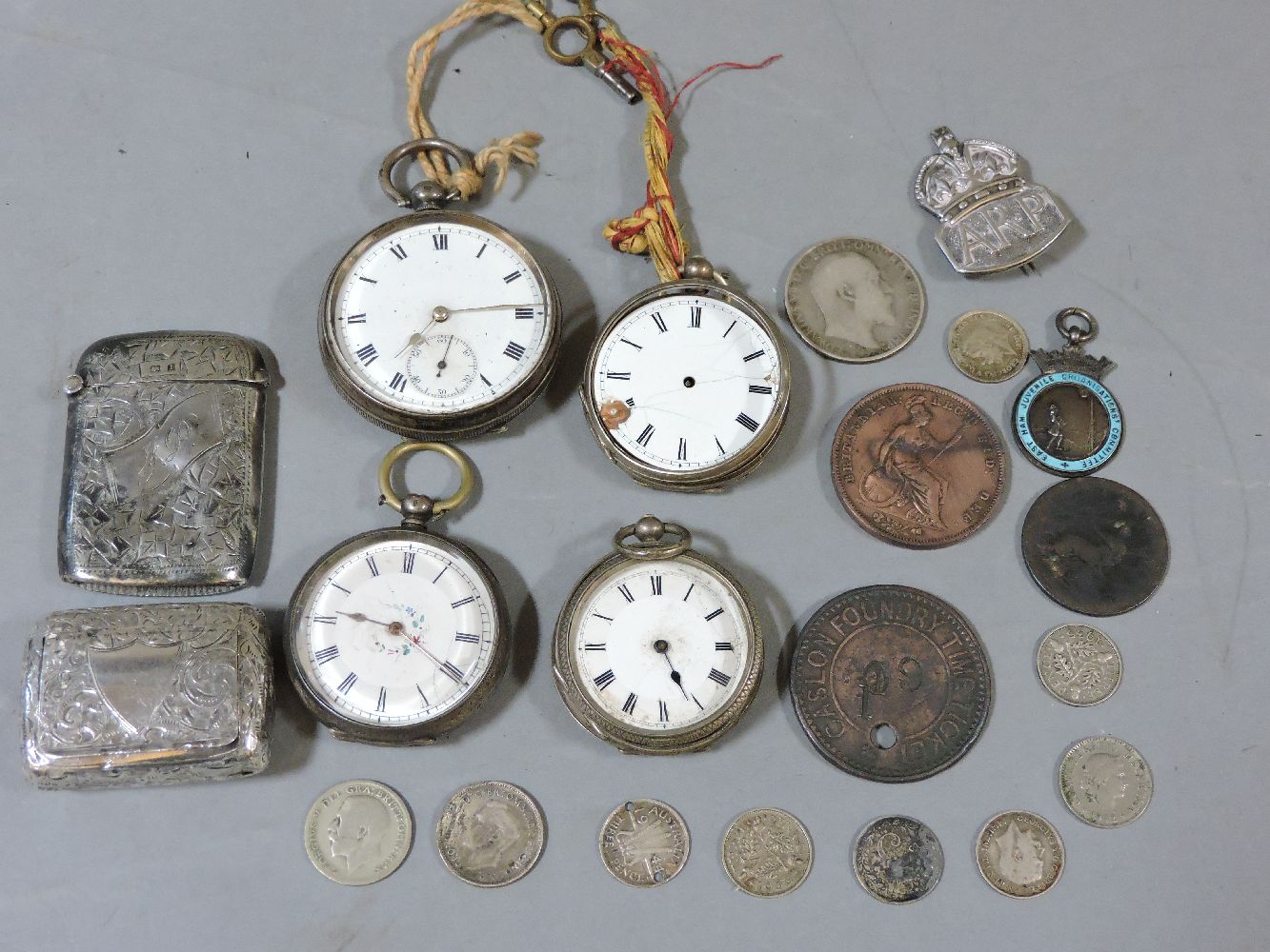 A silver ARP badge, vesta case, snuff box, four silver cased pocket watches, and coins