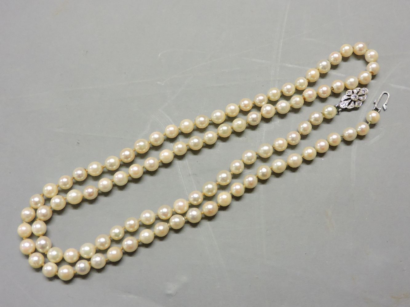 A single row uniform cultured pearl necklace, with a 9ct white gold and diamond set clasp