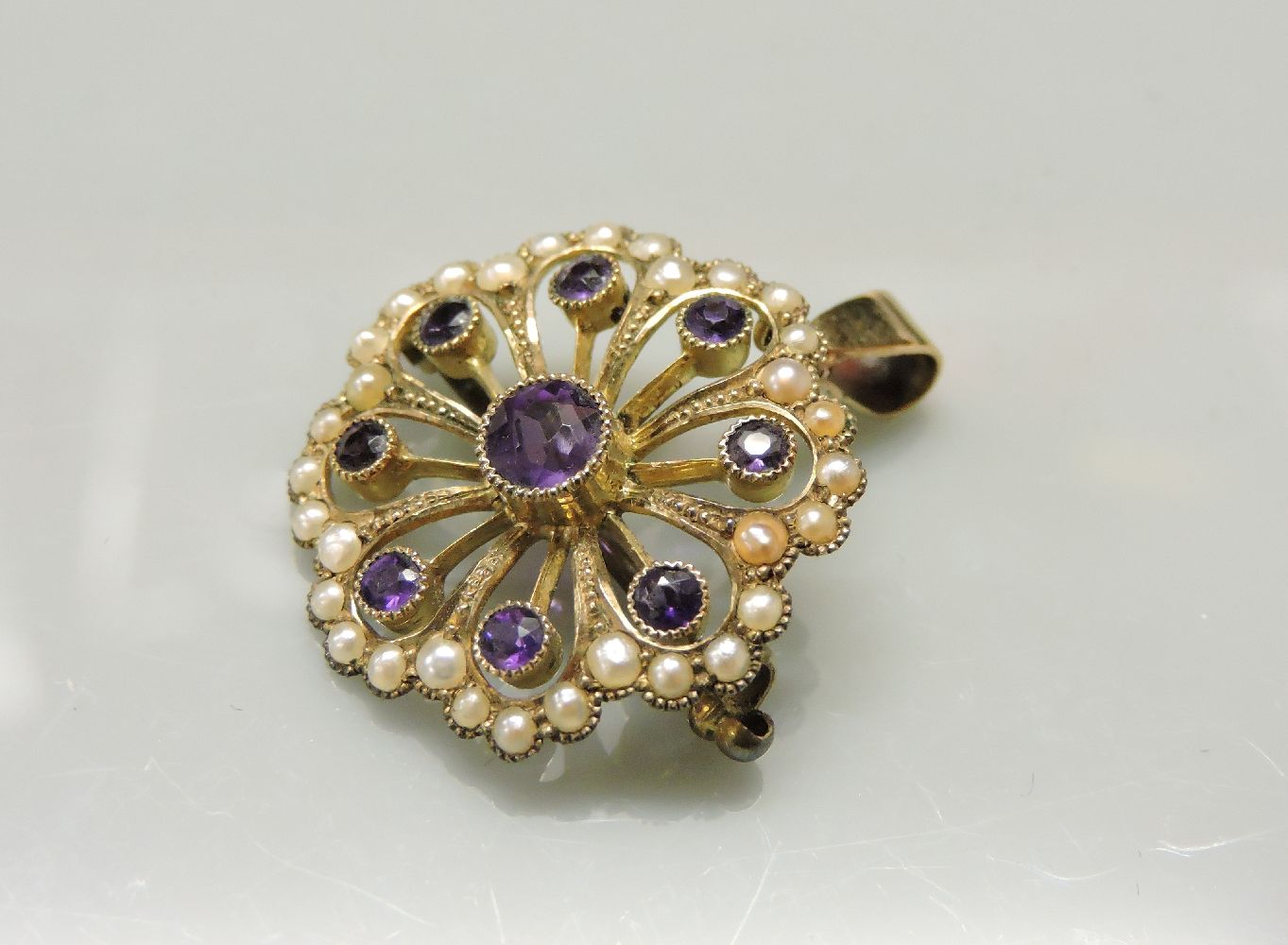 An Edwardian amethyst and split pearl brooch pendant, in the form of a flower, stamped 9ct