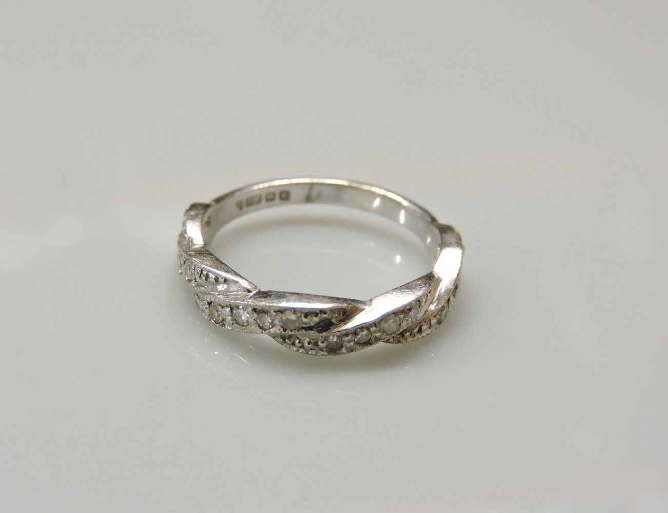 An 18ct white gold diamond set twisted ribbon half eternity ring