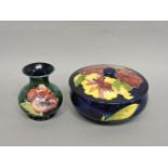 A Moorcroft 'Hibiscus' pattern pot and cover, 15cm diameter, and a small vase, 9cm high