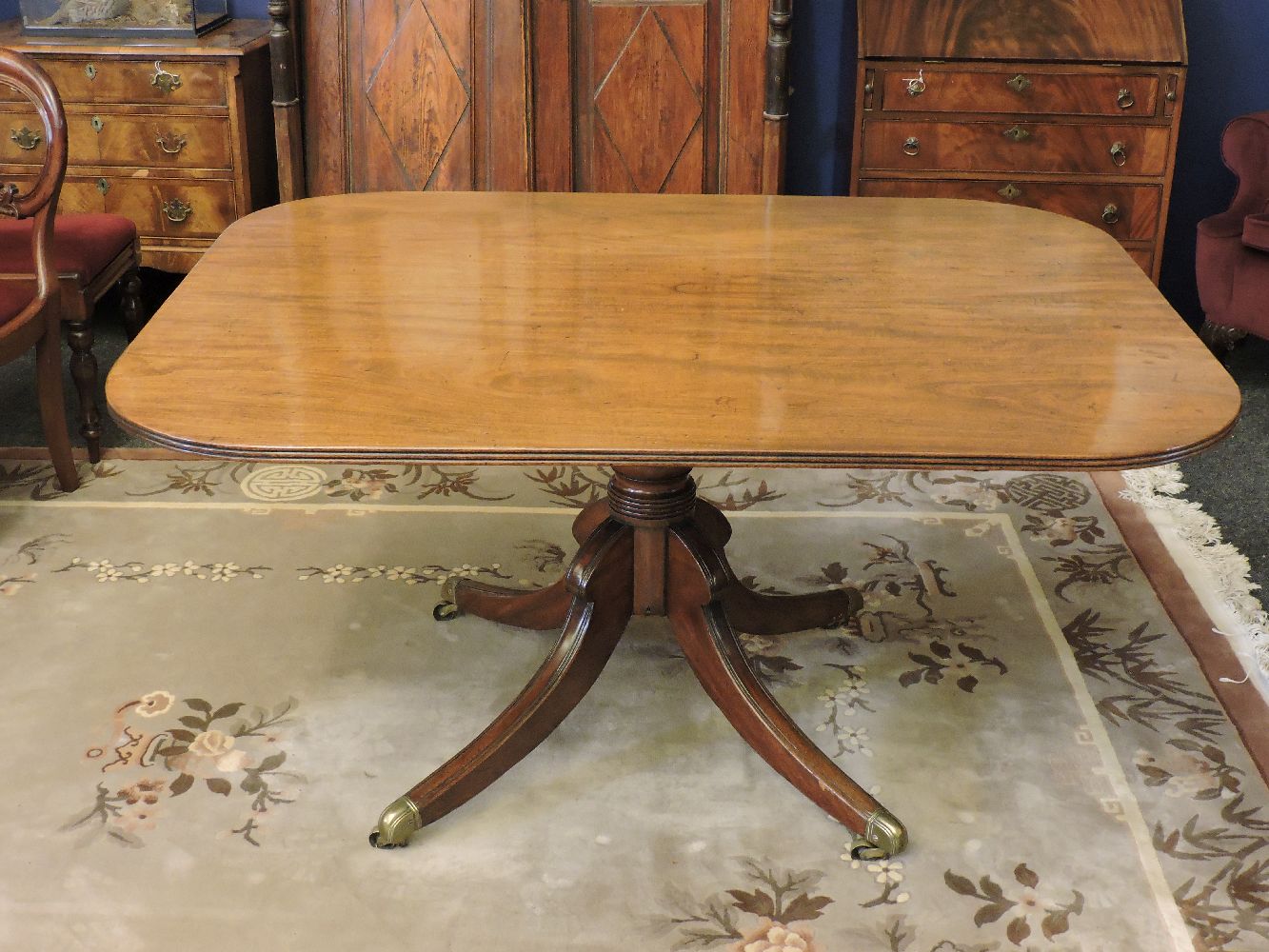 A George IV mahogany supper table, with a turned column on brass capped legs with castors