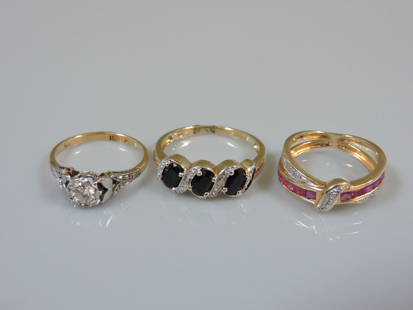 A single stone diamond ring, marked 18ct plat, a 9ct gold three stone sapphire ring with a diamond