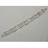 An Art Deco three row graduated cultured pearl bracelet, with pieced geometric bars stamped 9ct
