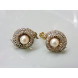 A pair of cultured pearl screw back earrings, with white stone set border, tested as approximately