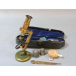 A cased student's brass folding microscope, a vegetable ivory tape measure with stanhope, two