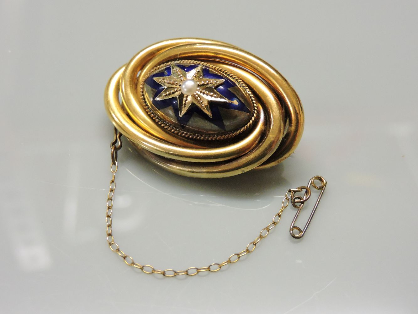 A Victorian gold knot brooch, with raised central oval boss decorated with an enamel and gold star