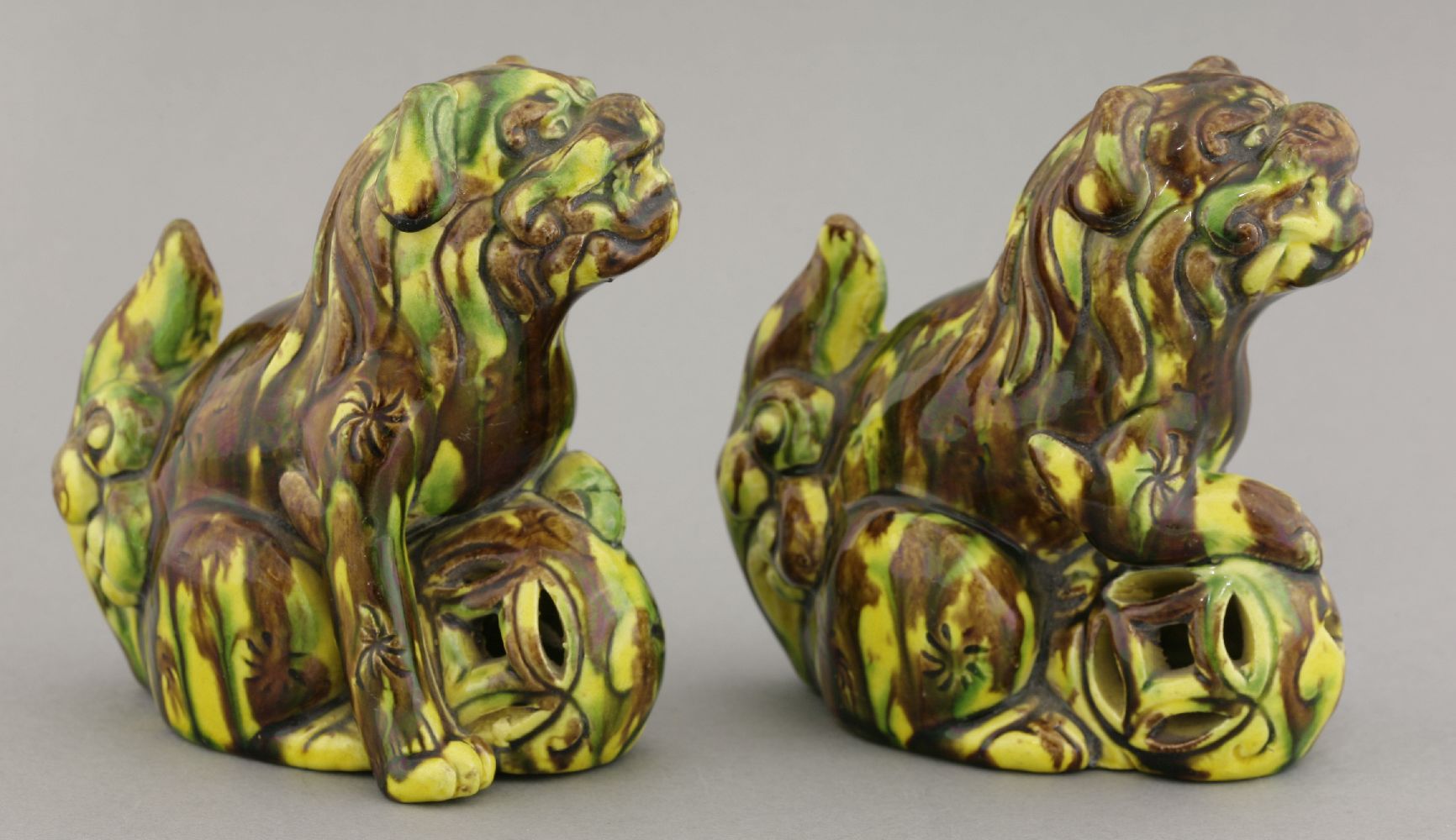 A pair of earthenware sancai Buddhist lions, circa 1880, each crouching over a pierced ball, its - Image 2 of 5