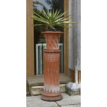 A pair of terracotta lattice moulded planters, each standing on fluted terracotta column supports,