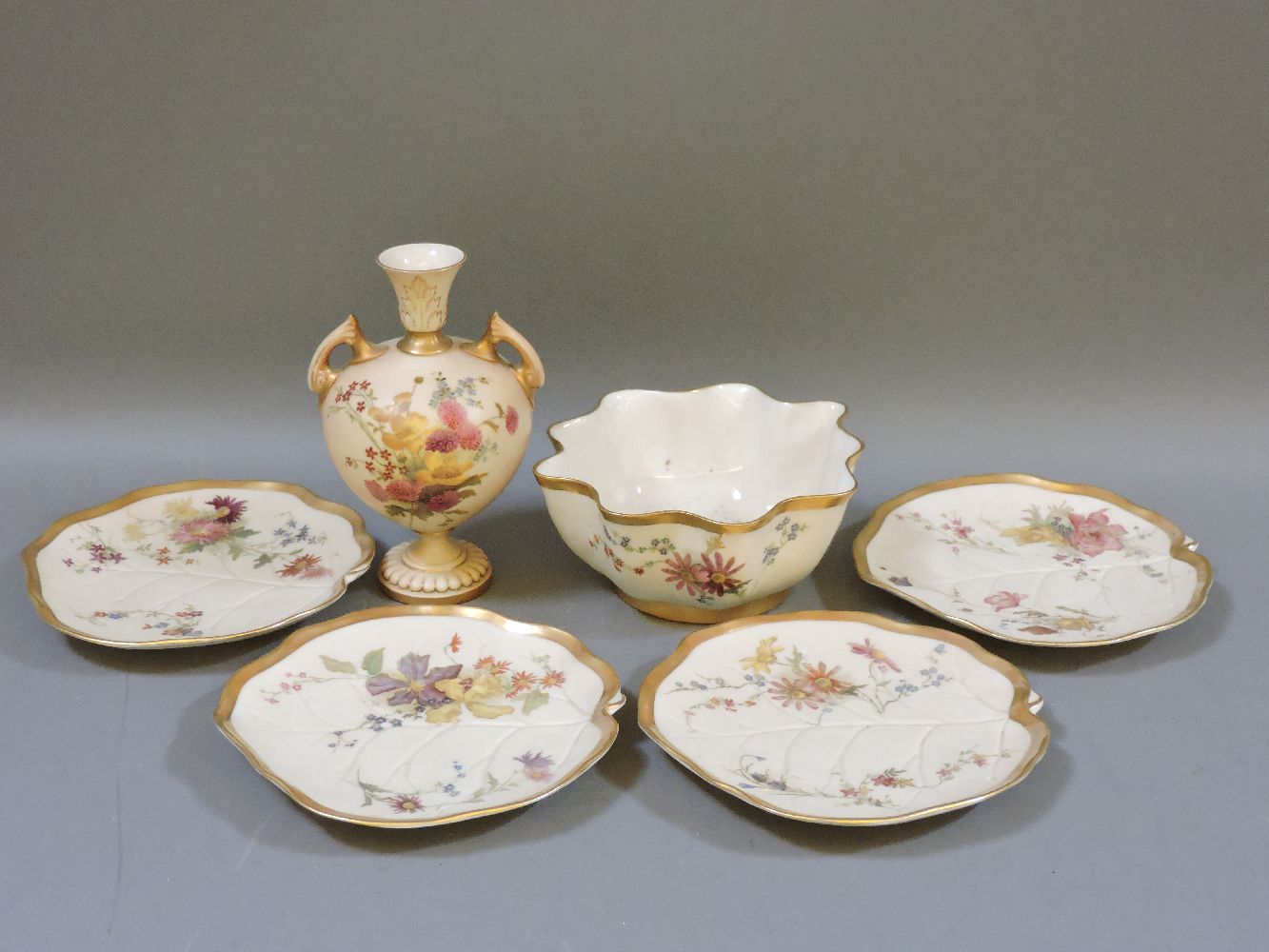 Two Royal Worcester twin handled vases, with painted floral pattern on blush ivory ground, shape