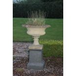 A pair of composition garden urns, of shallow campana form, standing on square tapering plinths,