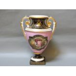 A Derby compagna urn, with a pink ground with a painted panel of flowers, with black and gilt bands,