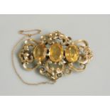 A Victorian three stone citrine brooch, in a scrolling gold mount, tested as approximately 9ct gold,