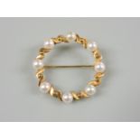 A gold circular brooch, set with cultured pearls stamped 18k