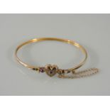 A gold sprung bangle, with heart centrepiece set with blue paste stones and split pearls, marked 9c,