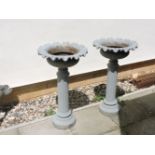 A pair of grey painted cast iron urns, on column supports