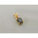 A single stone oval cut sapphire pendant, stamped 18k