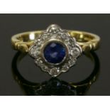 An 18ct gold sapphire and diamond lozenge shaped ring, with a central circular mixed cut sapphire,