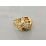 A gold mesh crossover bombé ring, set with three white paste stones, 5.6g