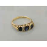 An 18ct gold three stone sapphire ring, with pairs of diamond set points