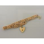 A gold three row gate link bracelet, marked 9c, with a later 9ct gold heart shaped padlock charm