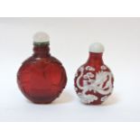 Two Chinese red glass scent bottles and stoppers, one overlaid in white with dragons, the other with