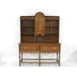 A 19th century Dutch oak dresser, the upper section with arch top cupboard flanked by shelves over