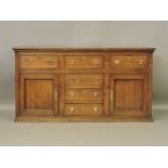 A George III oak sideboard, with three drawers over further central bank of drawers with cupboard to