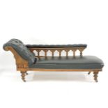 An oak chaise longue, black leather with carved frame and button upholstery, 190cm long