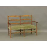 An Arts and Crafts oak two seater ladder back settee, shaped arms and double stretcher, 120cm wide