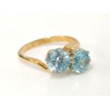 A gold two stone blue zircon crossover ring, marked plat and 18ct