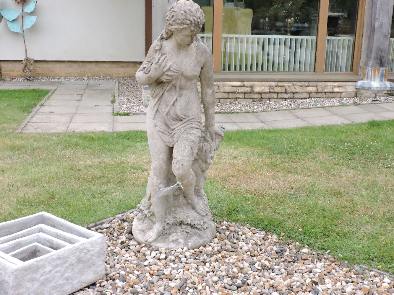 A composite garden statue of semi clad maiden, 104cm high, and a composite stone statue of a bathing