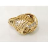 A gold mesh crossover bombé ring, set with three white paste stones, 5.6g