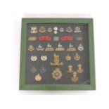 A framed collection of military cap badges, to include RMP Officer's silver (WM) cap badge, an