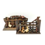 Two oak pipe racks, one in the form of a gate, with a collection of pipes, 28.5 and 32.5cm