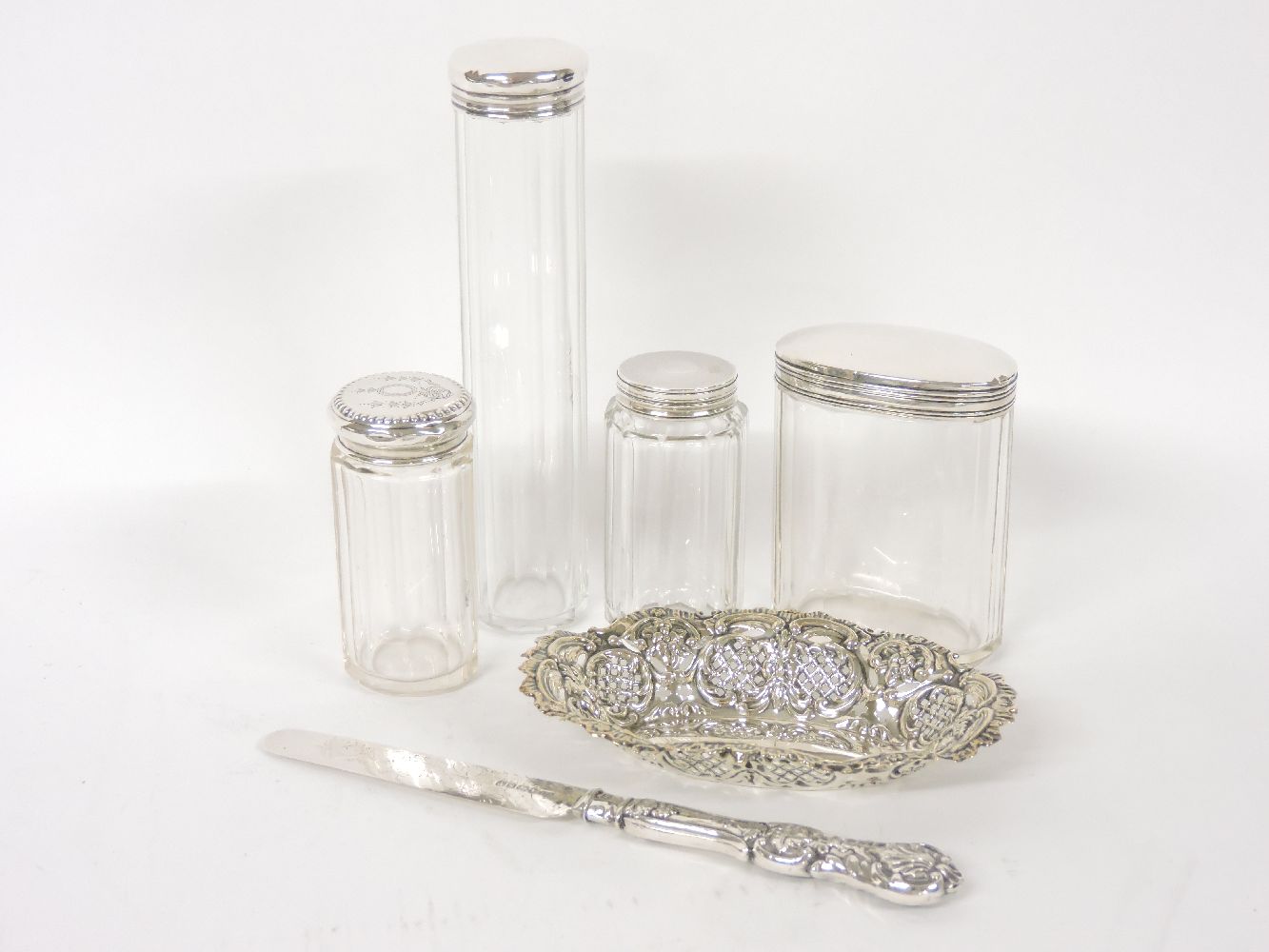 Four silver topped dressing table jars, a pierced silver dish, and a knife