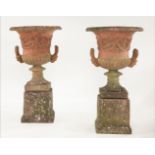 A pair of reconstituted stone campana urns, with tongue moulded edge and tight foliate scroll