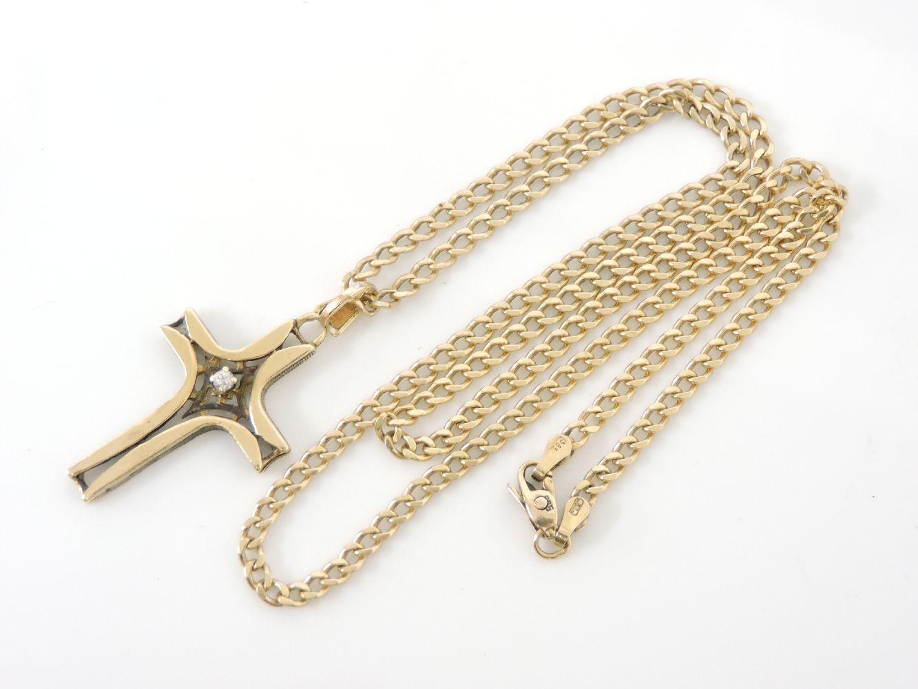 A gold single stone brilliant cut diamond cross, on a curb link chain, tested as approximately