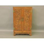 A Chinese mahogany cabinet, the panelled doors carved with prunus branches, 85cm wide, 39cm deep,