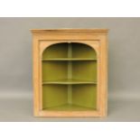 A pine hanging corner cupboard, with arched top, with shaped shelves, 116cm wide