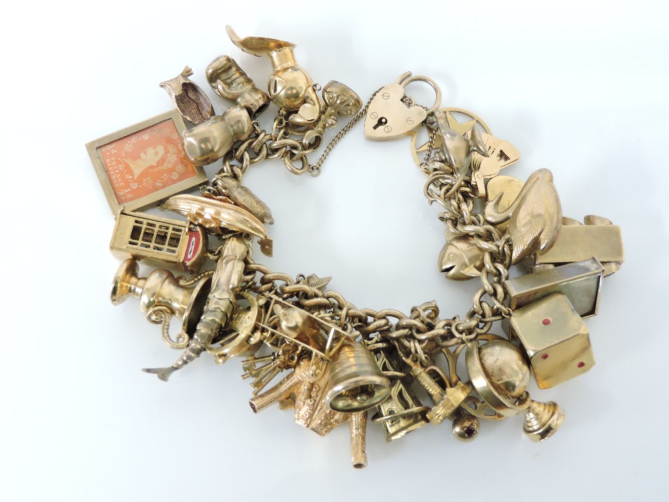 A 9ct gold charm bracelet, with a 9ct gold padlock and thirty-three assorted gold charms,