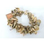 A 9ct gold charm bracelet, with a 9ct gold padlock and thirty-three assorted gold charms,