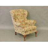 A 20th century wingback armchair, with carved legs, 79cm wide