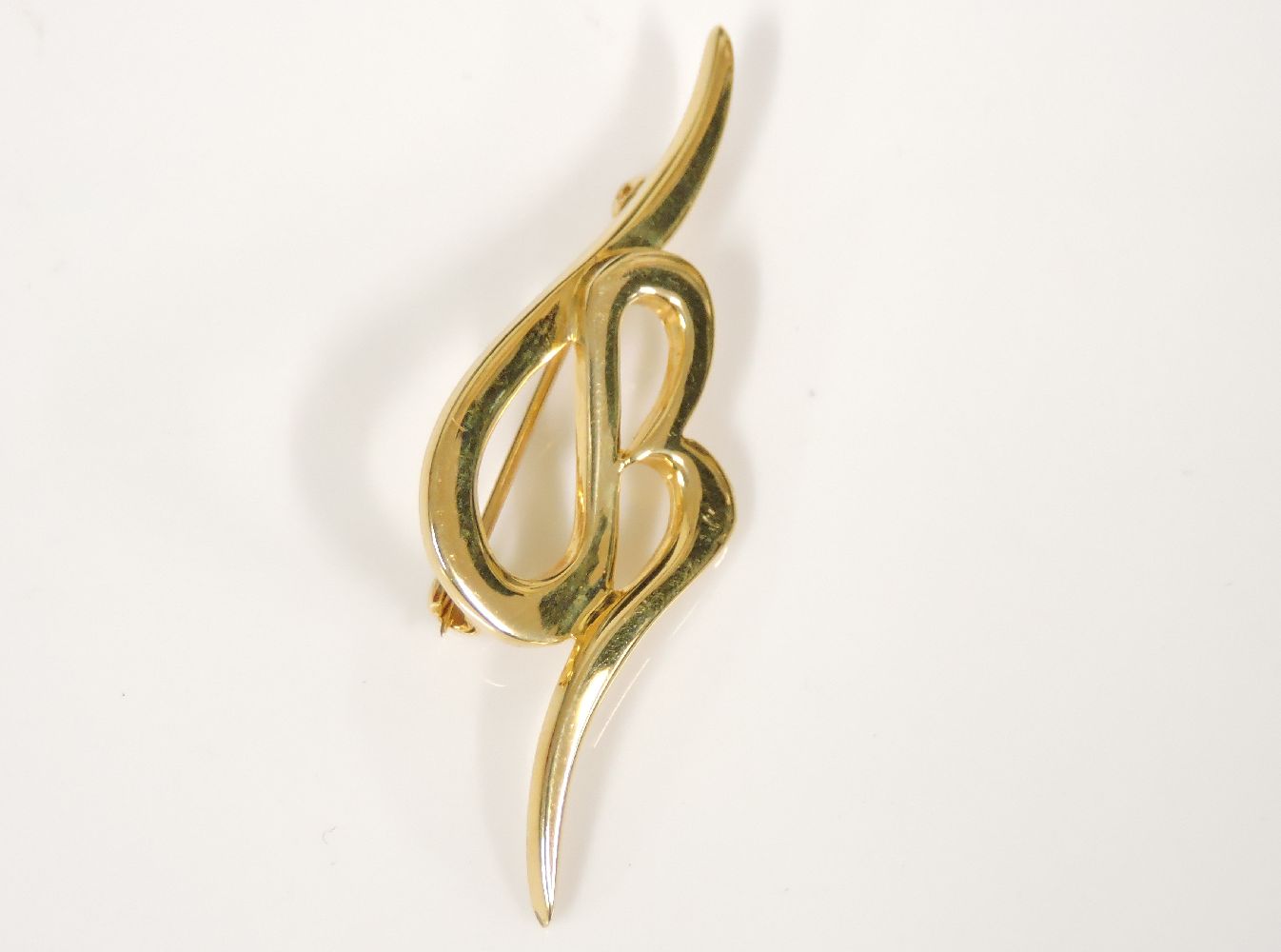 A gold scrolling initial brooch, tested as approximately 18ct gold, 8.0g