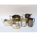 A silver cream jug and sugar bowl, a further sugar bowl and cream jug, a silver beaker, and a